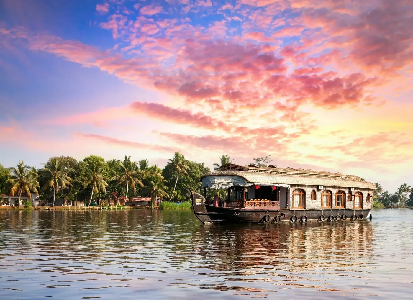 Traditional houseboat cruising Kerala backwaters at sunset